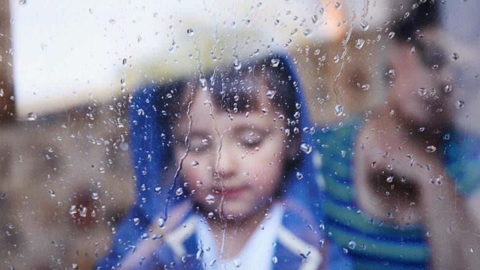 Child at wet window (posed by models)