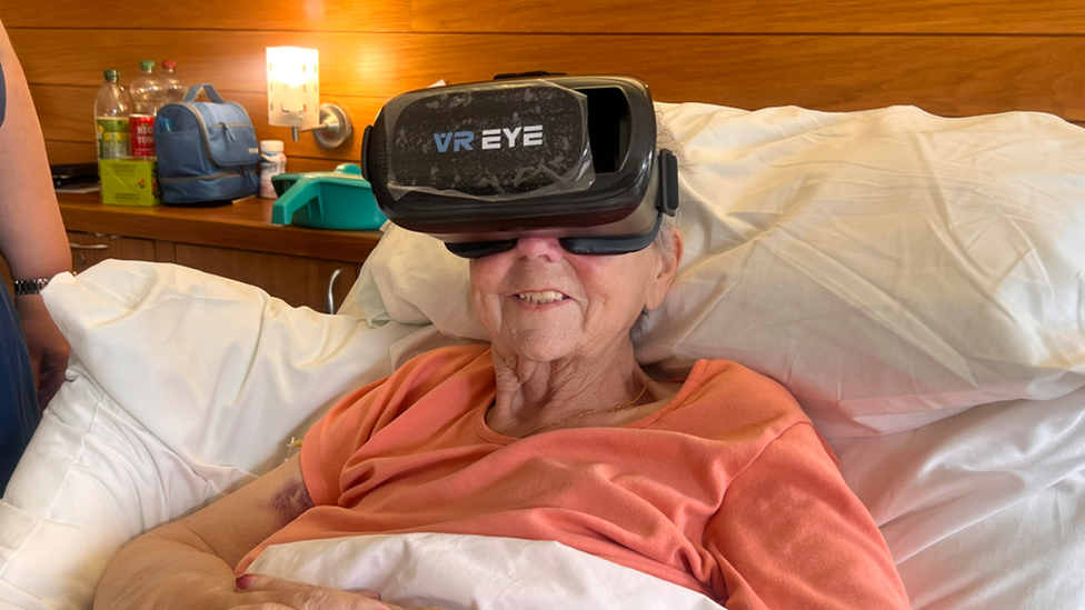 Woman in bed wearing VR goggles