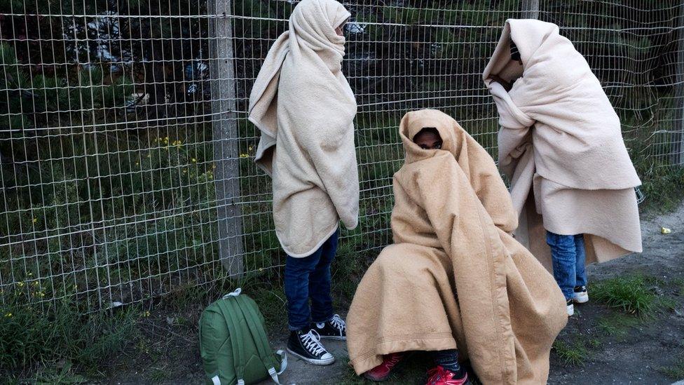 Migrants, who say they are minors, use blankets to protect themselves from the cold on a street after the dismantlement of the "Jungle" camp in Calais, France, October 27, 2016