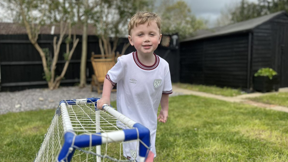 Jesse standing in his garden holding the crossbar of a small football goal