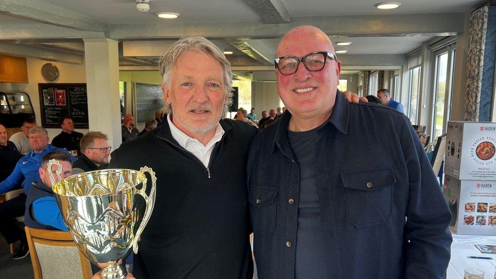 Russell Osman, who is holding a trophy, and Bryan Gunn