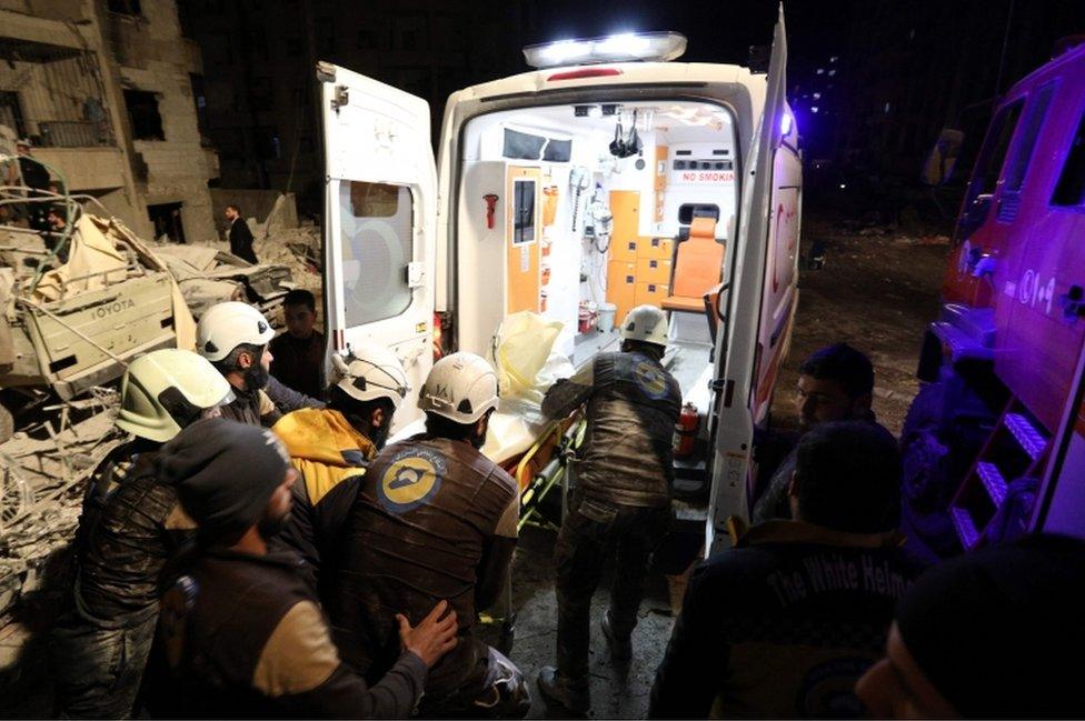 Syrian emergency personnel carry a victim into an ambulance after an explosion in a rebel-held area of Idlib