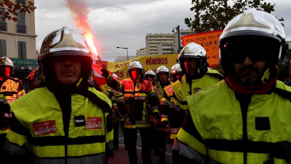 Firefighters hold placards and a smoke-bomb as they take part in a demonstration to protest against the pension overhauls, in Marseille, southern France, on 5 December, 2019