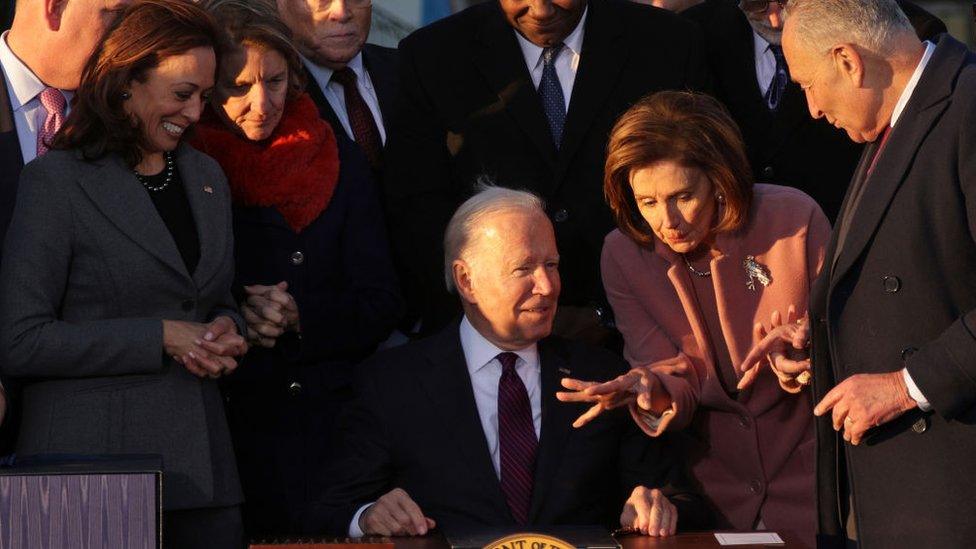 President Joe Biden talks to Speaker of the House Rep. Nancy Pelosi as Senate Majority Leader Sen. Chuck Schumer and Vice President Kamala Harris look on after signing the Infrastructure Investment and Jobs Act