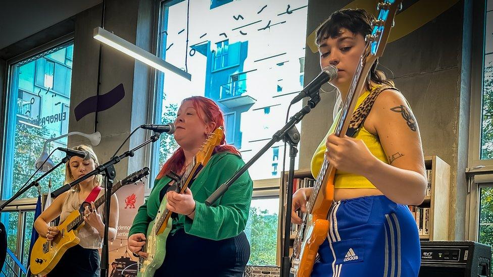 Adwaith, playing, three women holding bass and guitar on stage