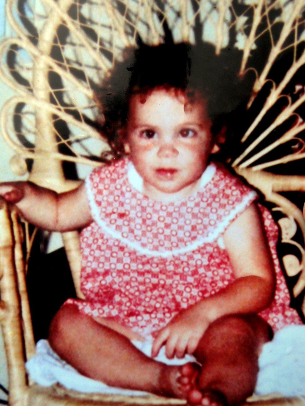 Katrice Lee, wearing a red-and-white dress, sitting on a chair