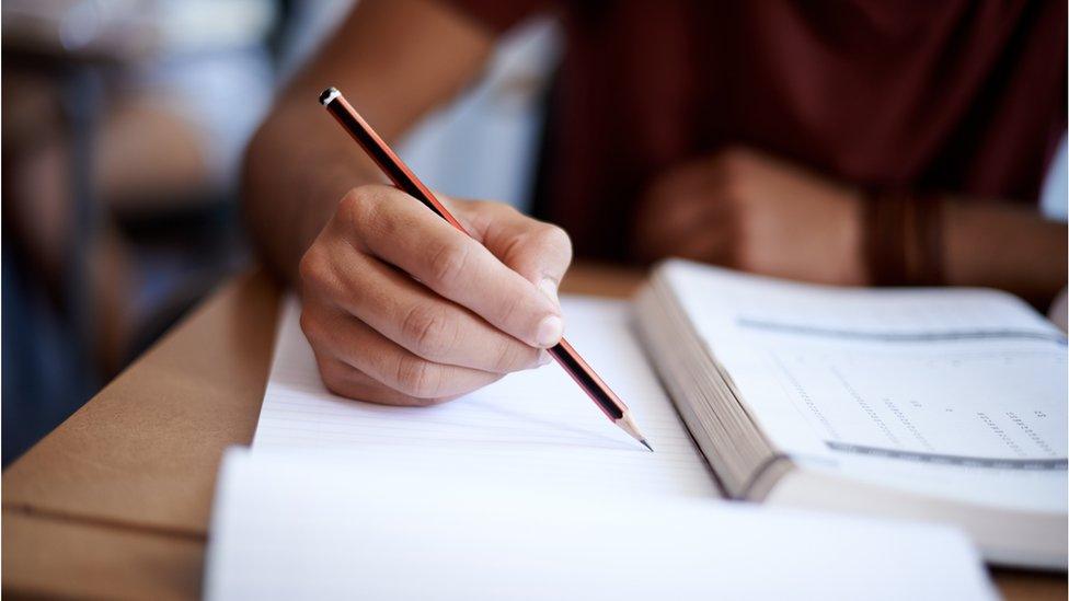 Close-up shot of a young man writing on a note pad