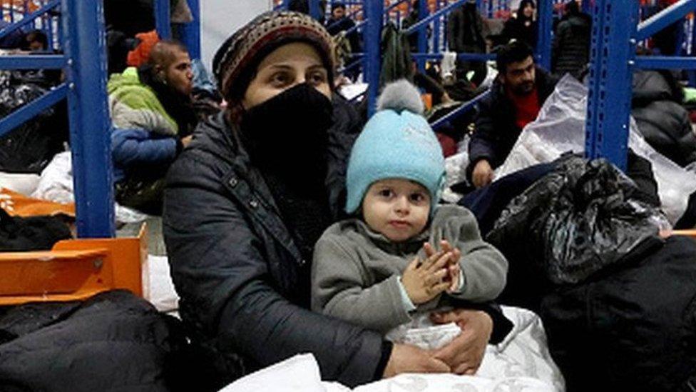 A woman holds a child in a temporary centre for migrants in Belarus