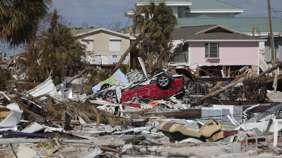 Debris from destroyed houses and a red car turned upside down.