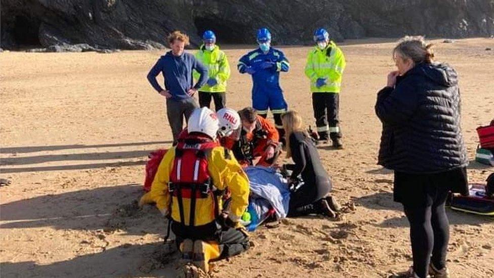 Woman being attended to on a stretcher on the beach