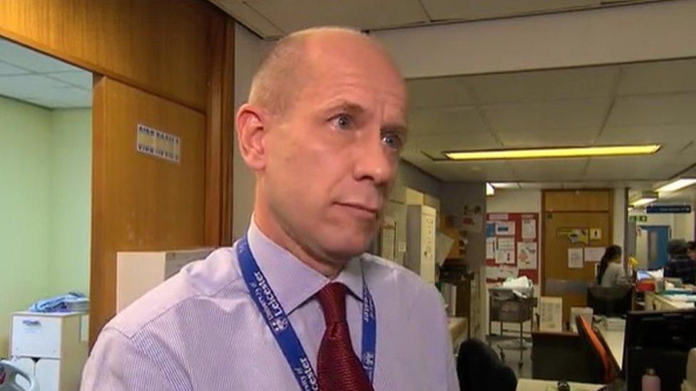 Man with very short hair standing in a hospital wearing a University lanyard