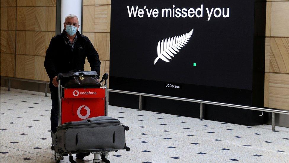 Man in front of a board at an airport saying "We've missed you"