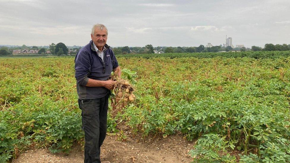 Andrew Mitchell holding up potatoes