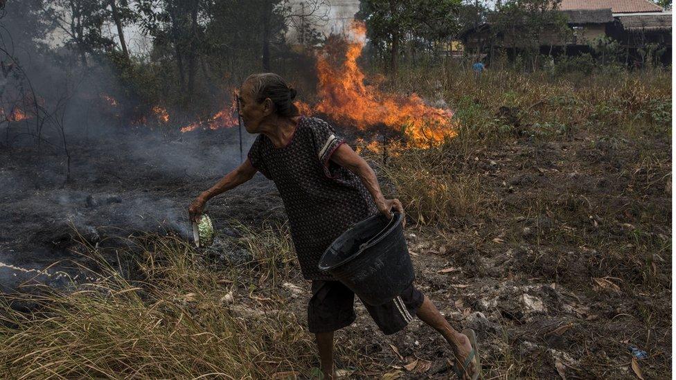 Woman fighting fire with a small bowl