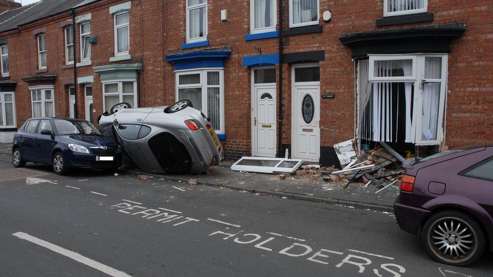 Car on side after crashing into house