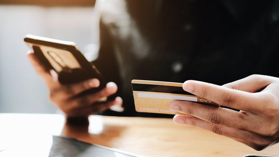 A woman holding a phone and a card