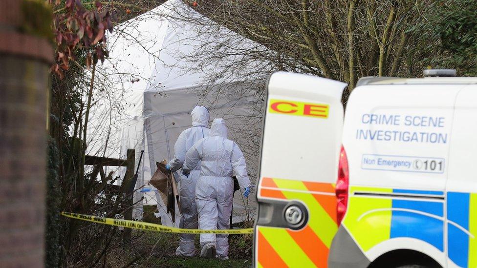 Forensic officers walking to a white tent