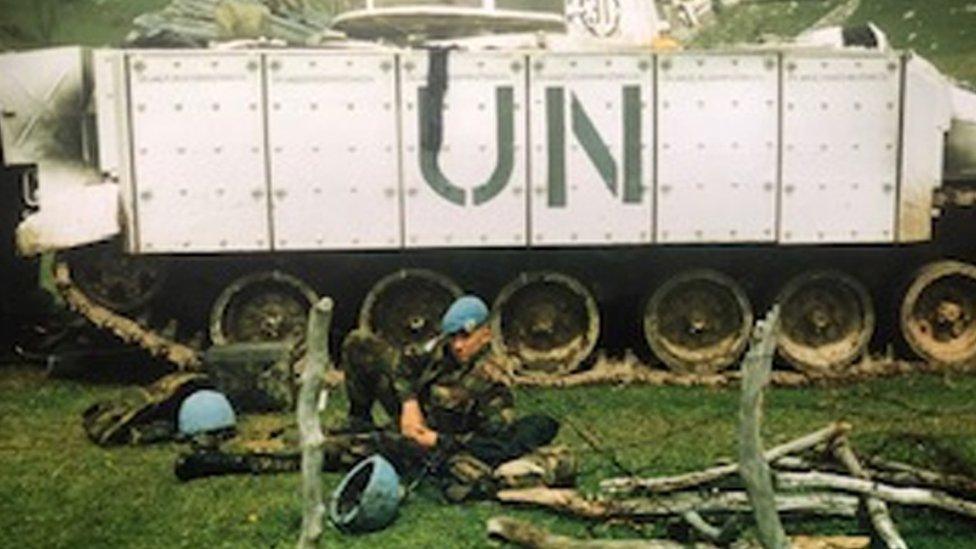 Shaun Pinner lying in front of a tank with UN written on the side