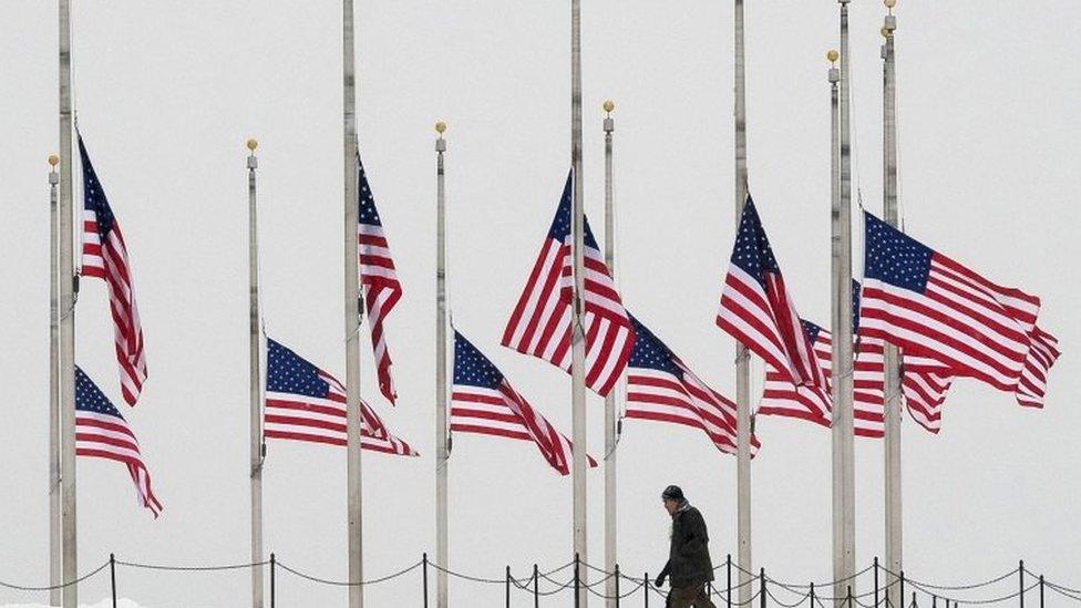 Visitors to the Washington Monument walk past flags flying a half-staff in honour of Supreme Court Justice Antonin Scalia on a wintry Presidents Day holiday in Washington, on 15 February 2016.