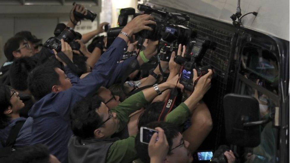 Photographers try to take pictures of Donald Tsang, former leader of Hong Kong, who is inside a prison bus leaving the high court in Hong Kong, Monday, Feb. 20, 2017.