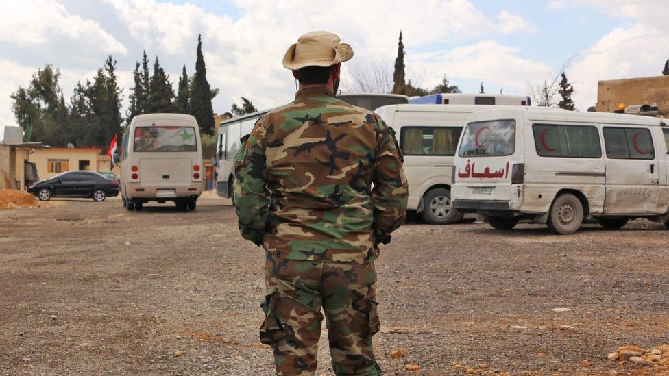 Syrian pro-government fighter stands near ambulances at the government-controlled al-Wafideen checkpoint, near the besieged rebel-held Eastern Ghouta (27 February 2018)