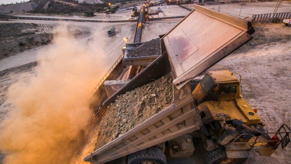 Dump trucks indicating different types of ore needed for correct blending in the processing cycle at Williamson