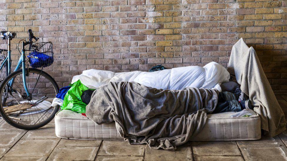 Person sleeping on a pavement on a mattress