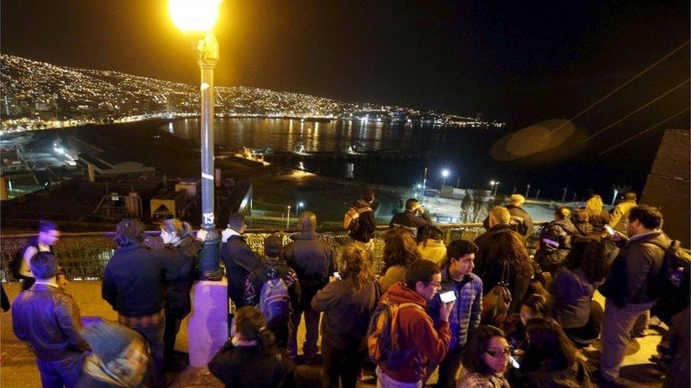 People stand and watch the ocean on Cerro Baron hill, in Valparaiso city on 16 September, 2015,