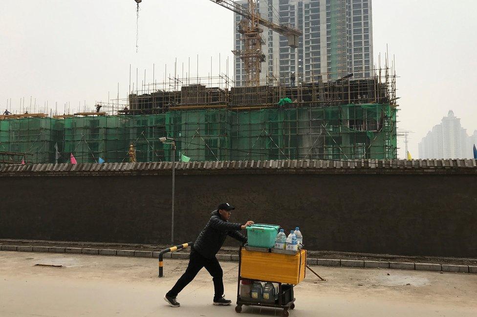 A man pushes his goods past a construction site in Beigaoying village on the outskirts of Shijiazhuang in north China's Hebei province, Wednesday, Oct. 26, 2016