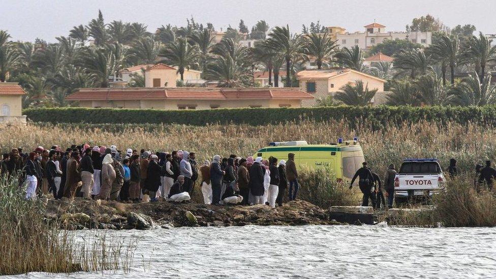 Relatives of the victims of a boat accident gather on the shore of Lake Mariout, near Alexandria, Egypt (23 February 2021)