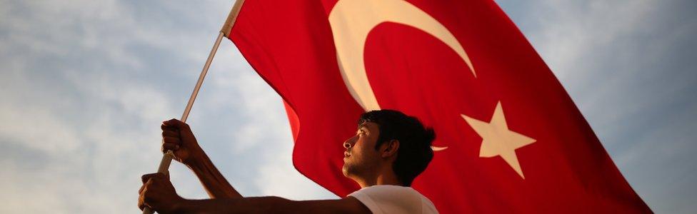 A man waves a national flag as thousands of people march to protest against the deadly attacks on Turkish troops, in Izmir, Turkey on 9 September, 2015