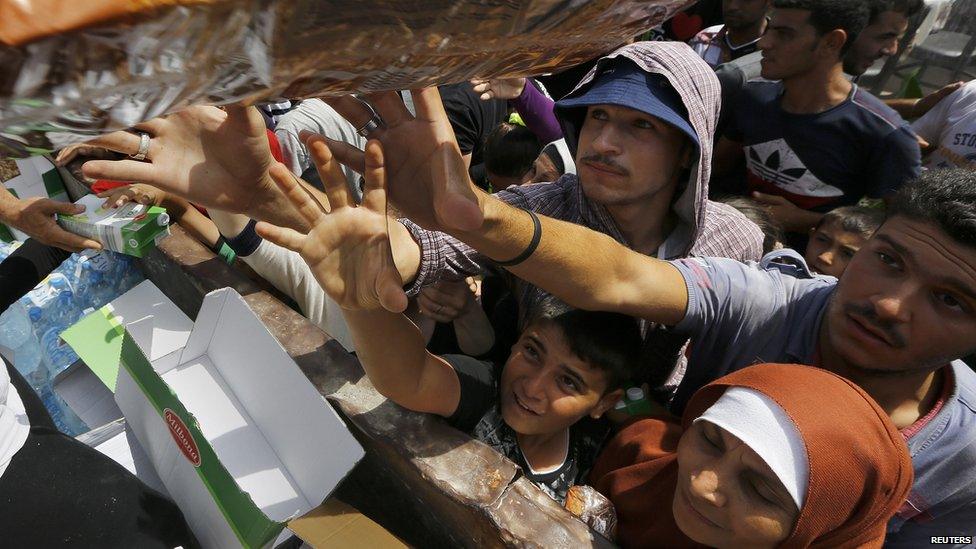 Syrian refugees and other migrants struggle to get dry food during aid distribution by workers of the Kos municipality on the Greek island of Kos 14 August 2015.