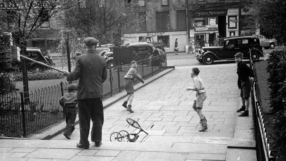 A man with a broom chases away a group of unruly boys from a Dundee park