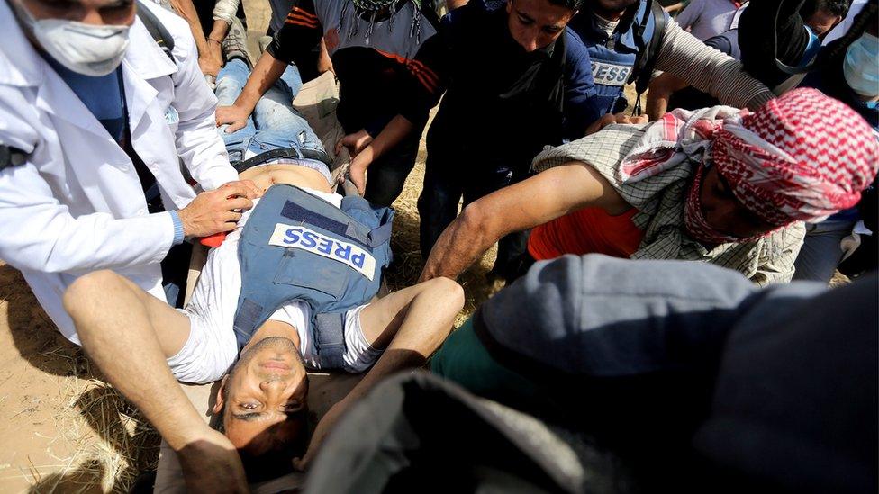 Mortally wounded Palestinian journalist Yasser Murtaja, 31, is evacuated during clashes with Israeli troops at the Israel-Gaza border