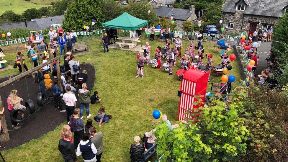 A crowd of people gathered watching a band play in the park