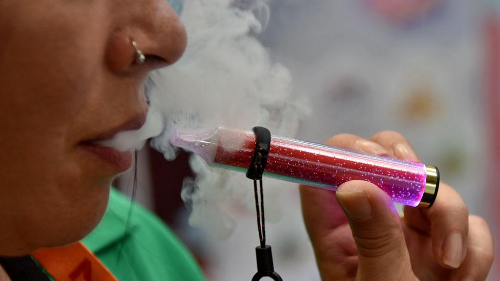 A woman smokes a disposable vape