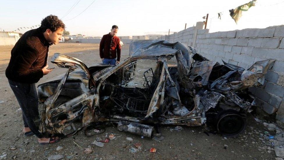 Men look at the wreckage of a burnt car after a suicide bomber detonated a pick-up truck in Sadr City on Wednesday (15 February 2017)