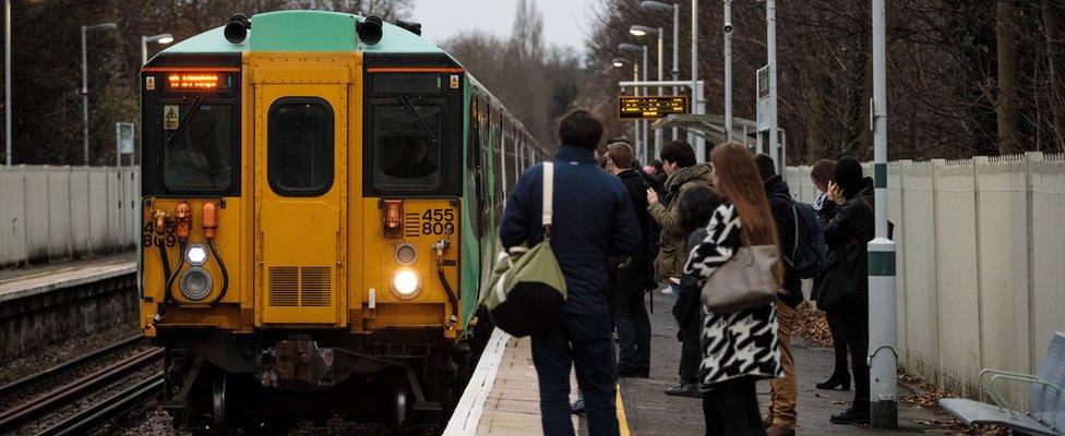 Commuters on a platform as a train arrives