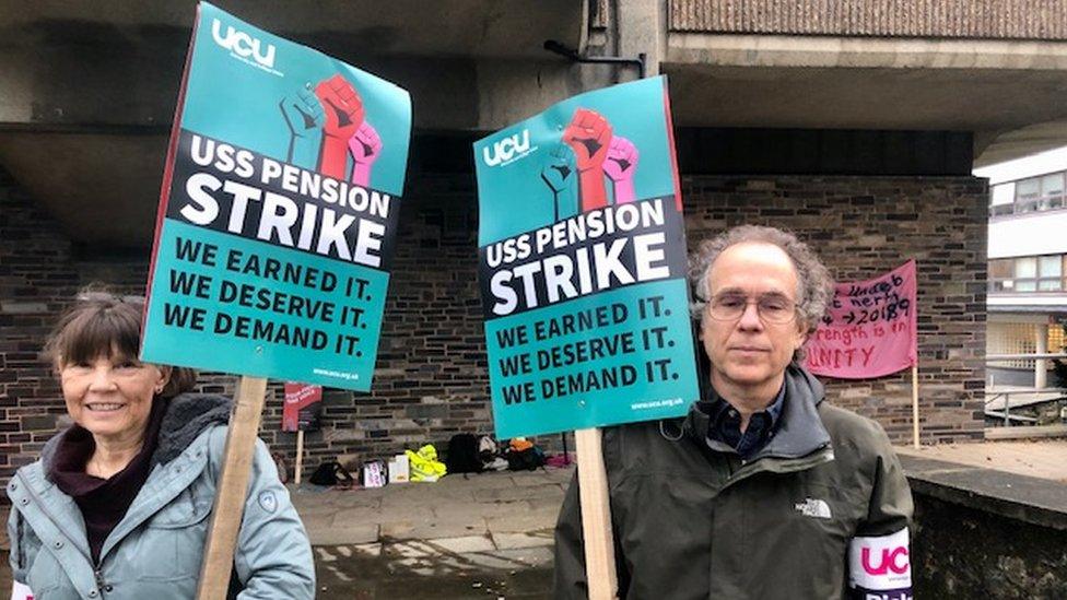 Two staff holding up placards in protest