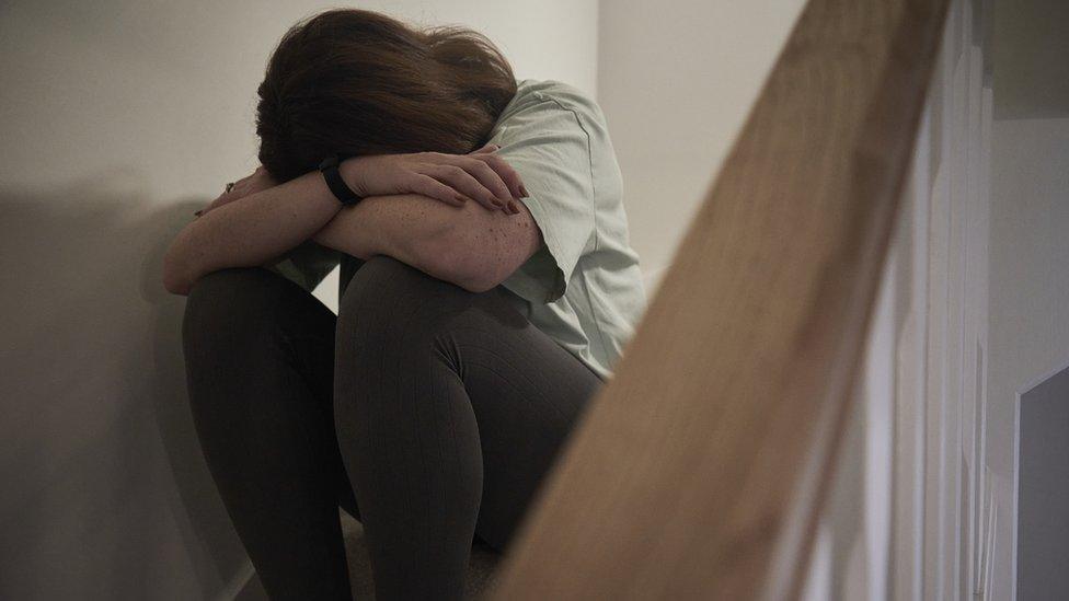 Woman on staircase with head in arms