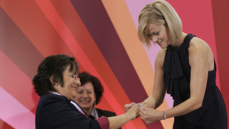 US actress Reese Witherspoon (R) puts a campaign bracelet on biochemist and domestic violence survivor Brazilian Maria da Penha (L) during an event to spread a message of female empowerment, in Sao Paulo, Brazil, on August 28, 2008.