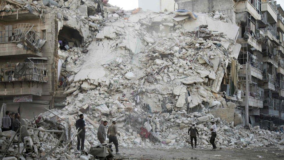 Rescue workers search for victims amid rubble of a destroyed building following reported air strikes in the rebel-held Qatarji district of Aleppo (17 October 2016)