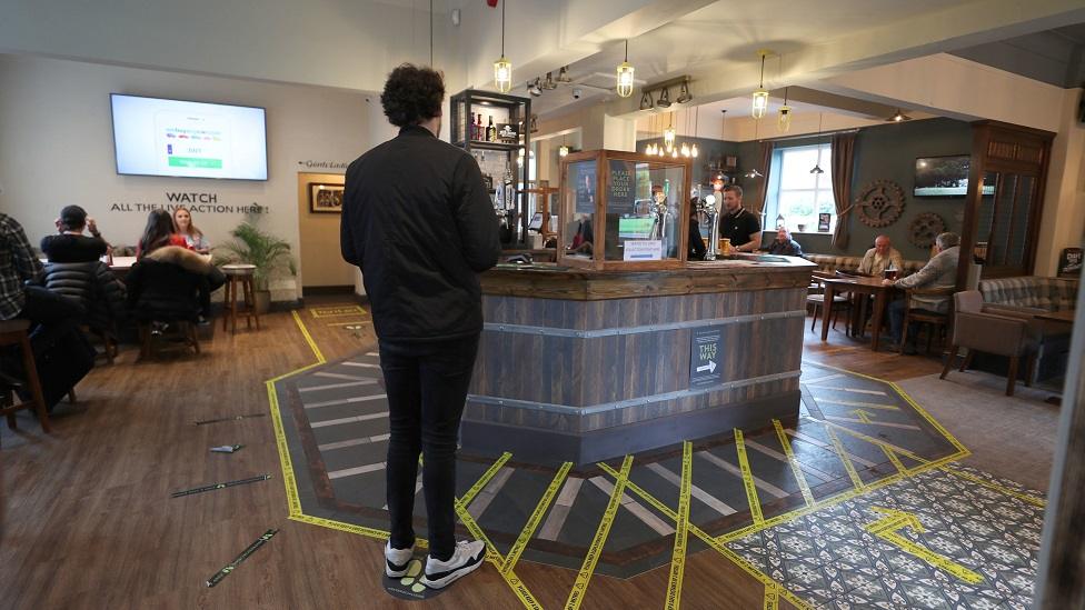 A customer stands back from the bar at the Rocket pub in Liverpool