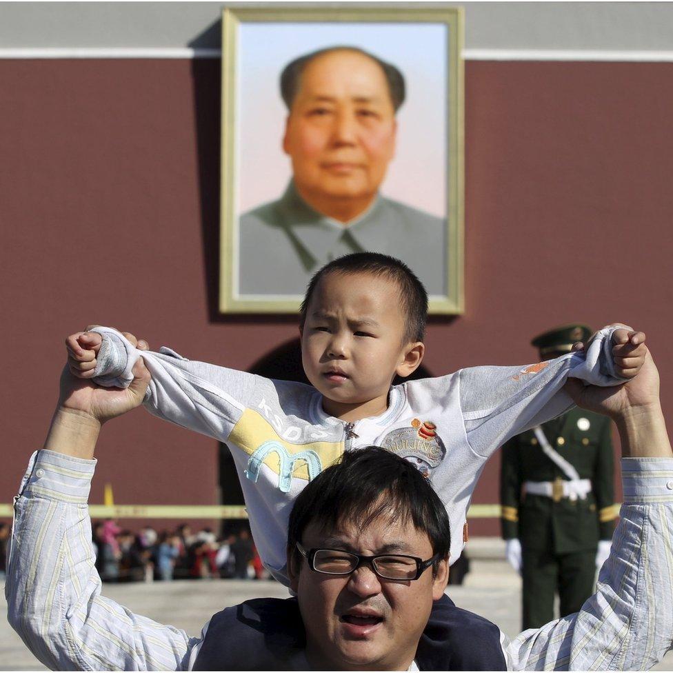 A boy sits on his father's shoulders as they pose for a photograph in front of the giant portrait of late Chinese chairman Mao Zedong on the Tiananmen Gate, in Beijing, China, October 2011.