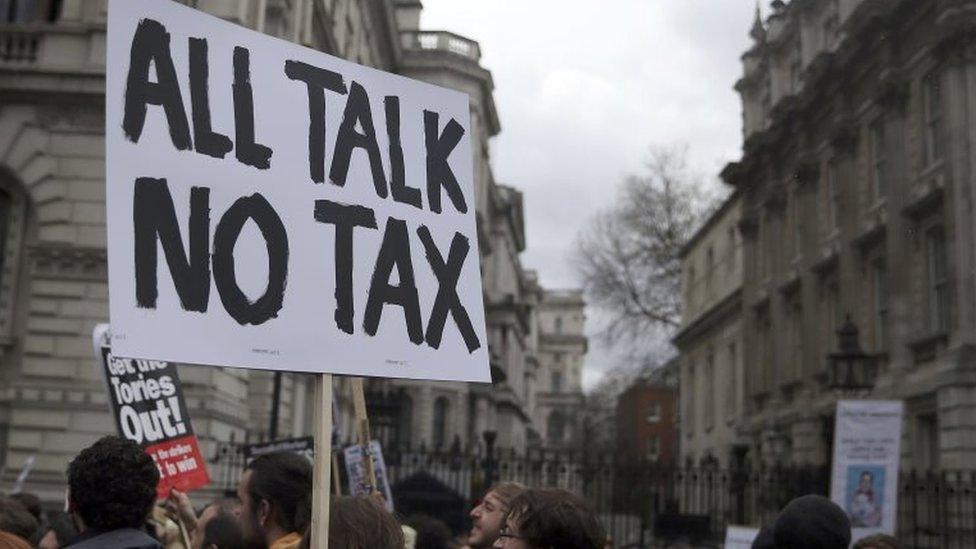 Demonstrators hold placards during a protest outside Downing Street in Whitehall, central London, 2016