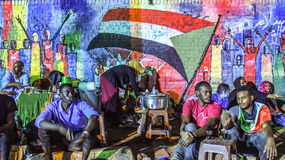 Sudanese protesters sit in front of a recently painted mural during a demonstration near the army headquarters in the capital Khartoum, Sudan - 24 April 2019