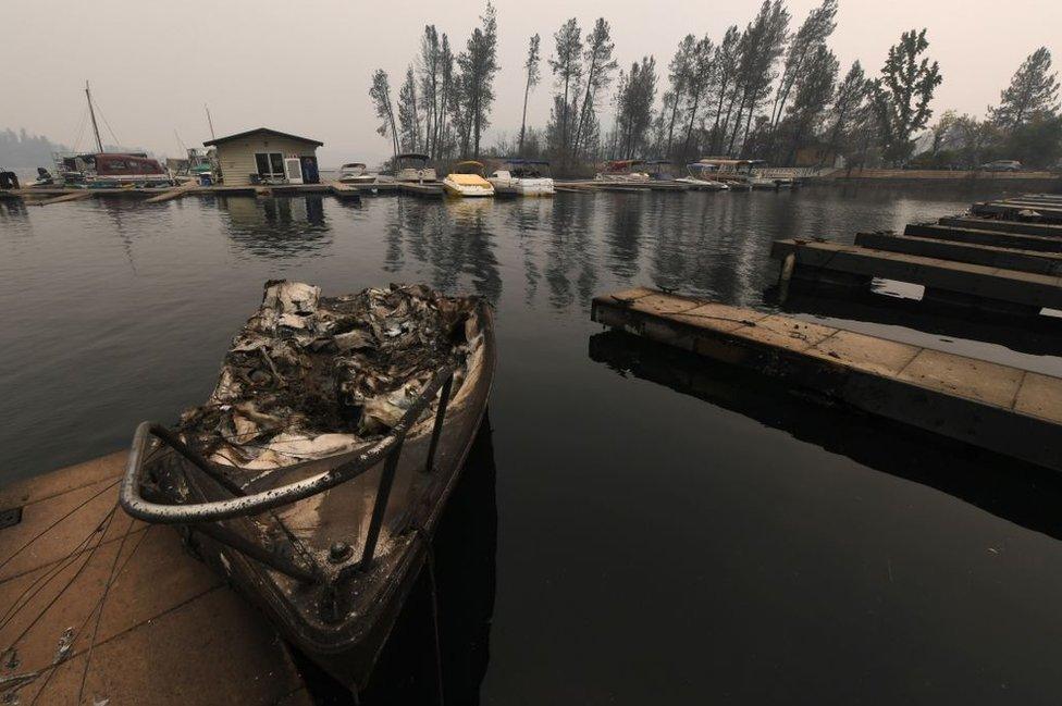 A burnt boat sits at a marina on Whiskeytown Lake