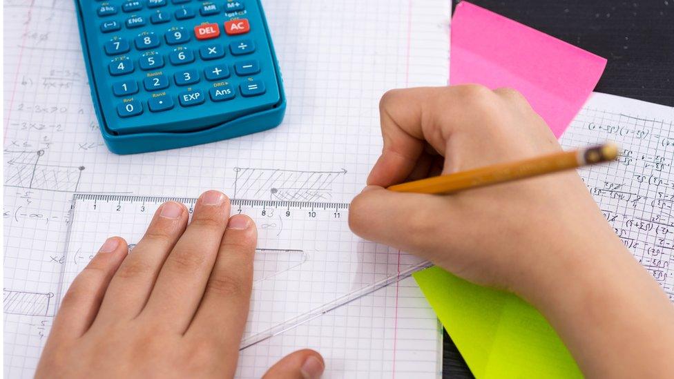 Child's hands doing maths with a calculator