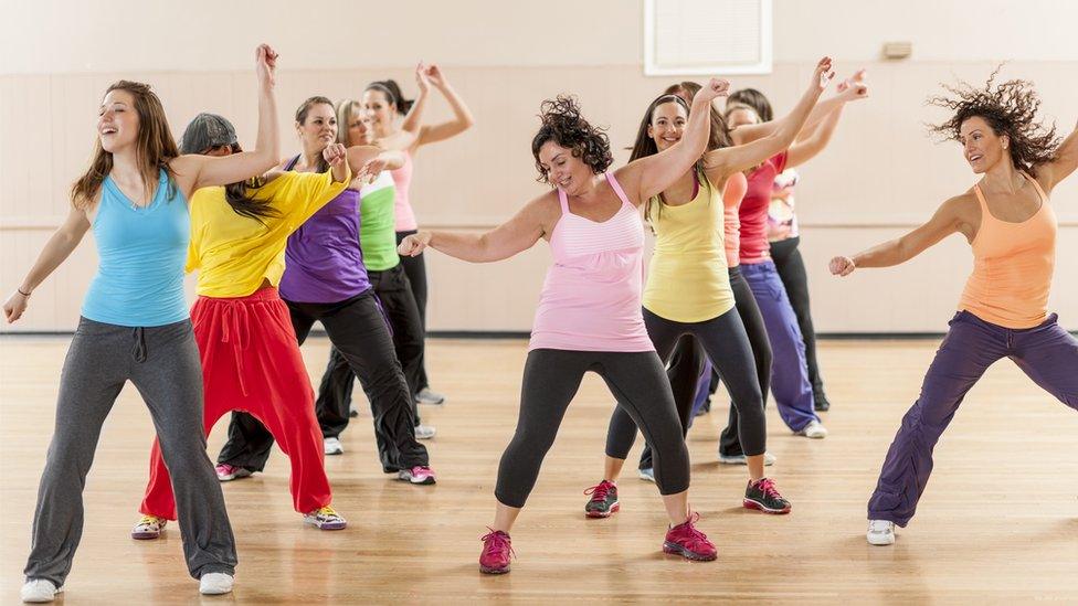 A group of women working out and dancing together during a class in a gym studio.