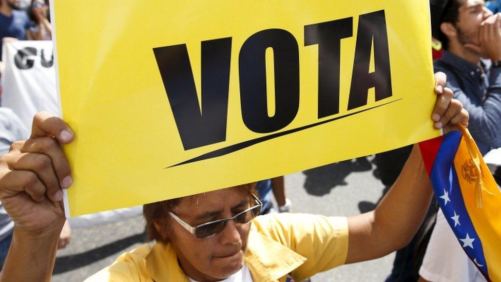 An opposition supporter hold a placard that reads "Vote" while she takes part in a rally against President Nicolas Maduro"s government on University Student Day, in Caracas, November 21, 2015.